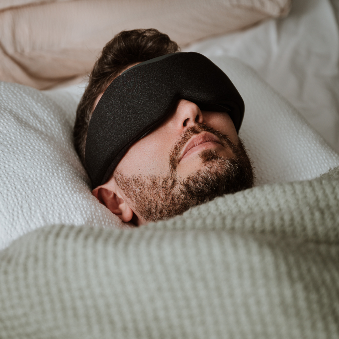 Man sleeping comfortably with Midnight Black Aura Smart Sleep Mask on bed
