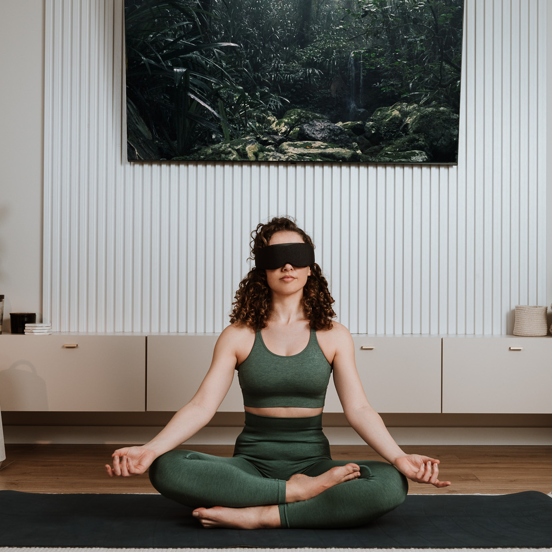 Woman meditating while wearing Midnight Black Aura Smart Sleep Mask in a peaceful indoor setting
