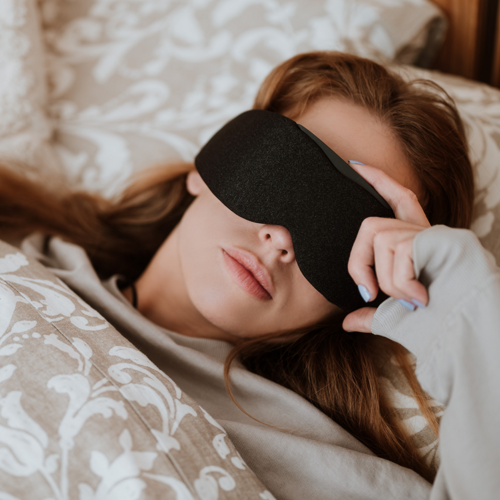 
                      
                        Woman side-sleeping comfortably on the bed with Midnight Black Aura Smart Sleep Mask
                      
                    